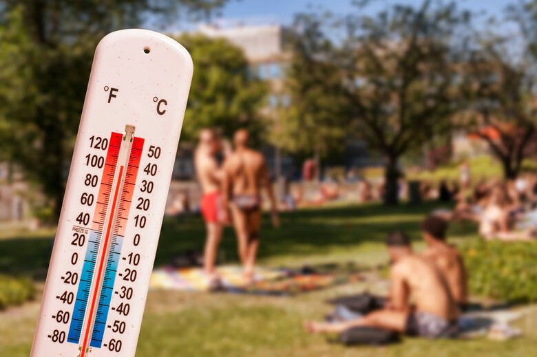 Termometr przed ludźmi opalającymi się w parku