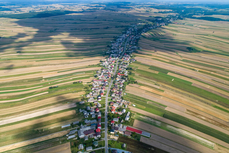 Wąski pas budynków skryty między kilometrami pól – tak niesamowicie z lotu ptaka prezentuje się niewielka wieś w Polsce.