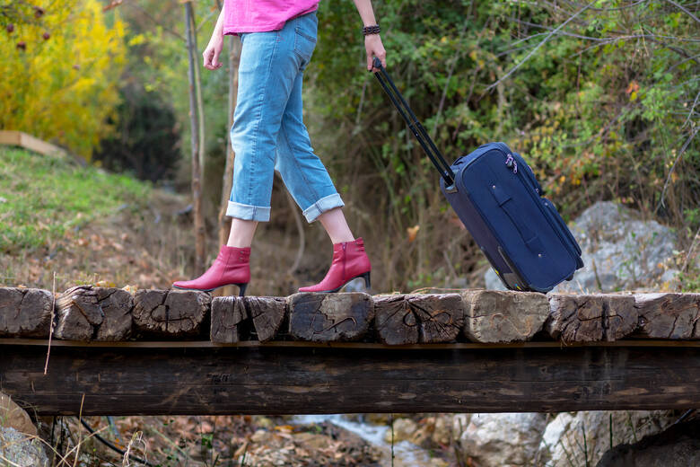 Kobieta na obcasach z walizką na szlaku