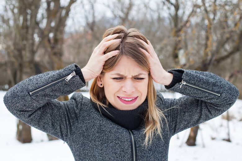 Kobieta bez czapki w zimie cierpi na ból głowy 