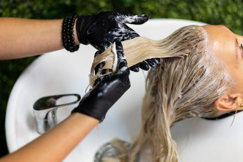Kobieta na fotelu do mycia głowy z preparatem kosmetycznym na włosach