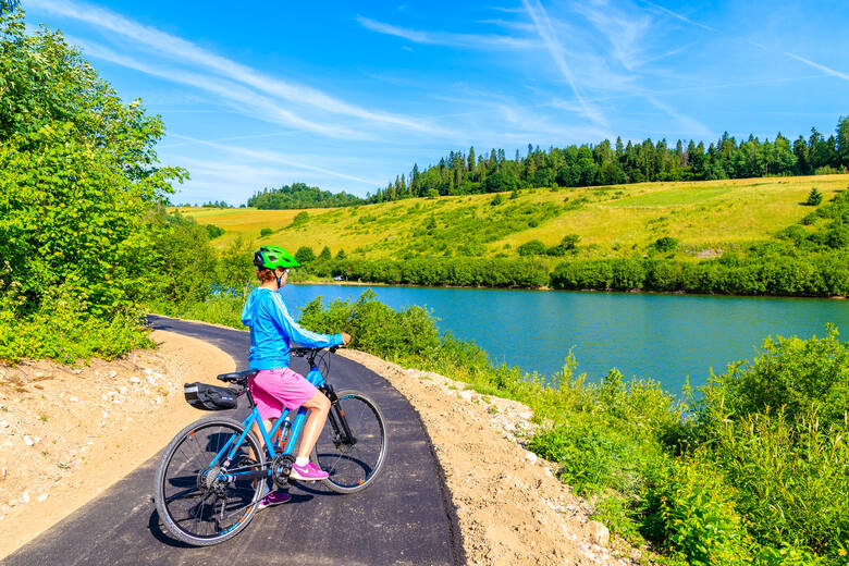 Kobieta stojąca z rowerem na drodze rowerowej Velo Dunajec