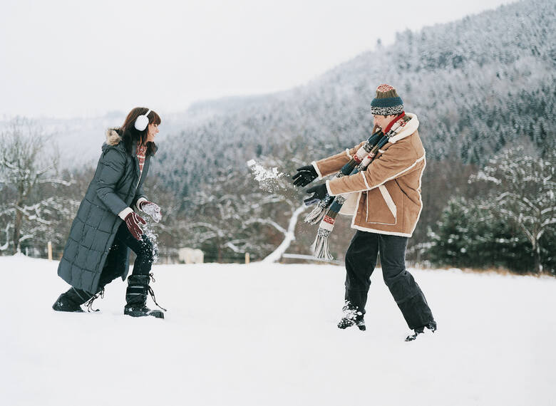 Kobieta i mężczyzna w zimowych ubraniach rzucają się śniegiem