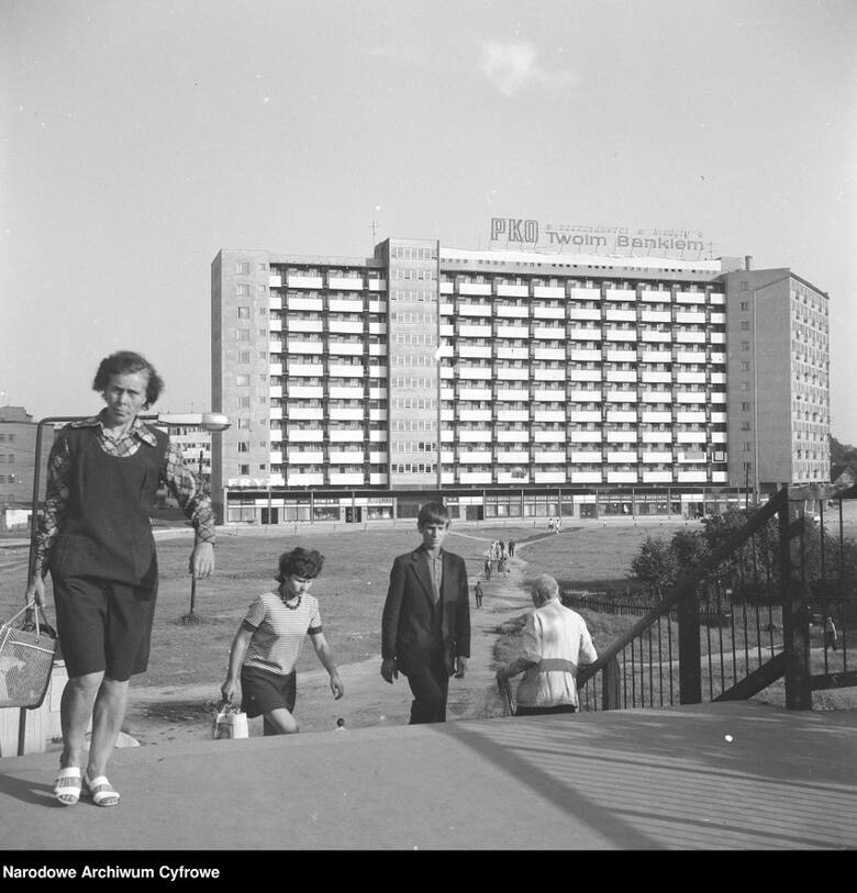 Nowe osiedle w pobliżu dworca kolejowego. Na bloku mieszkalnym widoczny neon "PKO twoim bankiem". Na pierwszym planie kobieta z siatką (1973/08)