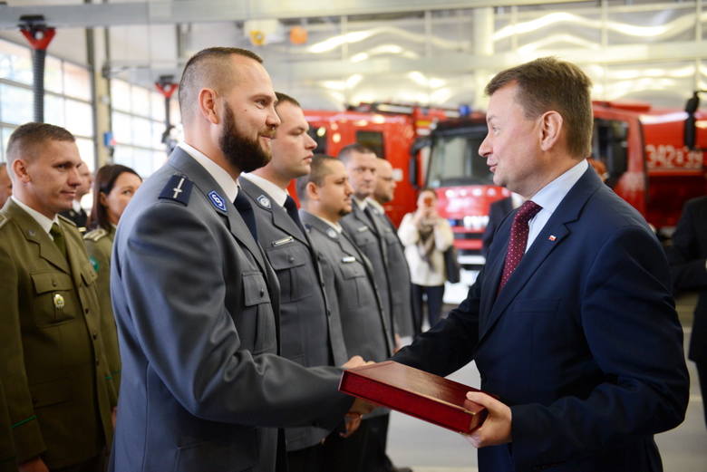 Minister administracji Mariusz Błaszczak wręecza pamiątkową plakietkę Pawłowi  Lorentowiczowi  ze straży granicznej
