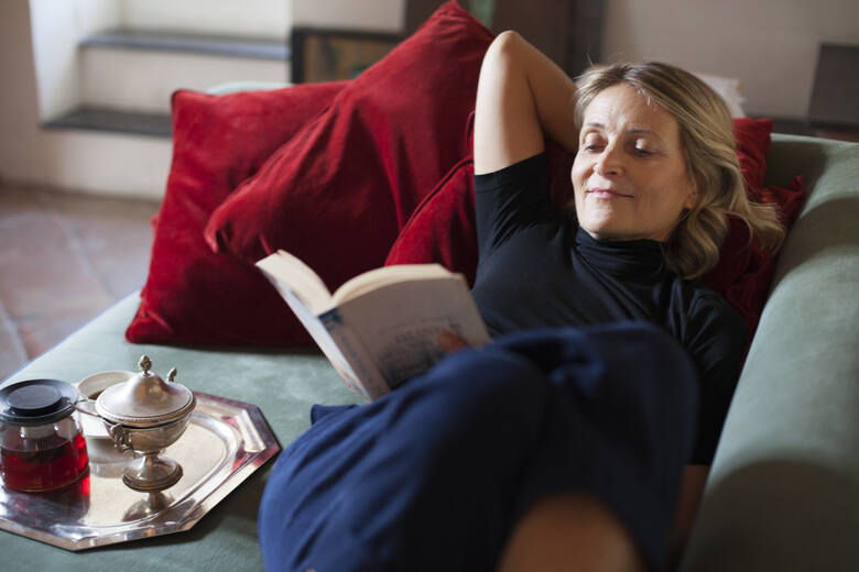 Kobieta w średnim wieku relaksuje się z książką i herbatą