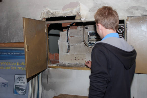 Pracownik sklepu pokazuje dziurę w ścianie, przez którą do wnętrza dostali się włamywacze. Miejsca jest wystarczająco dużo, by człowiek mógł się przecisnąć.