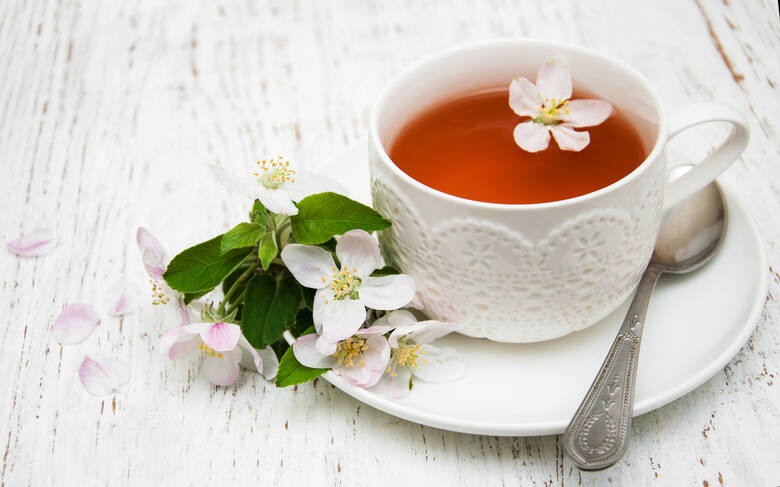 Herbata z kwiatów jabłoni w białej filiżance i kwiaty jabłoni