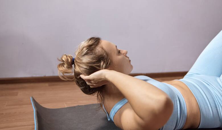 Młoda kobieta wykonuje ćwiczenie na mięśnie brzucha