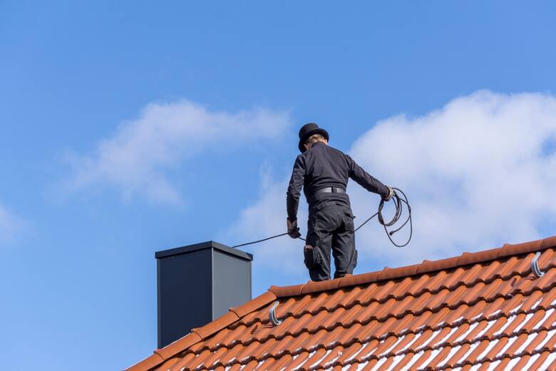 kominiarz na dachu domu czyszczenie przewodów kominiarskich