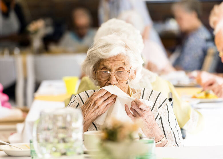 Seniorka kończy posiłek w restauracji i ociera usta serwetką