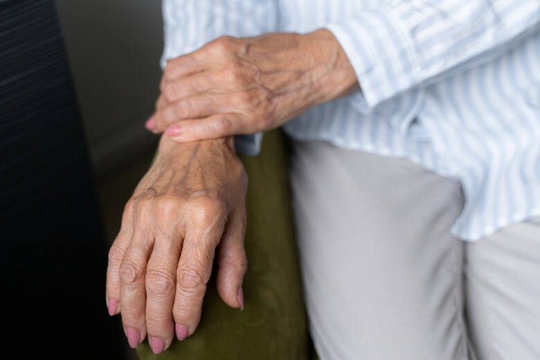 Starsza kobieta trzyma się za nadgarstek ręki ze spuchniętymi stawami