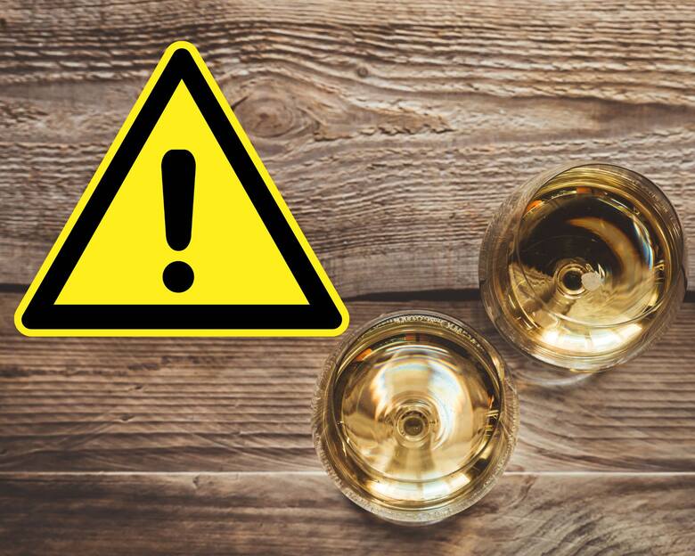 Kieliszki z białym winem i znak ostrzeżenia