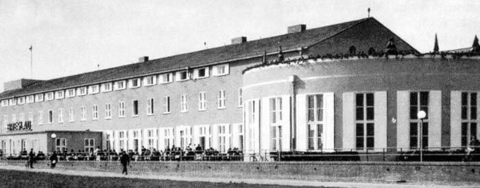 Budynek portu z wieżą kontroli lotów przy ulicy Szybowcowej. Znajdują się w nim przedszkole, komisariat policji i mieszkania prywatne.