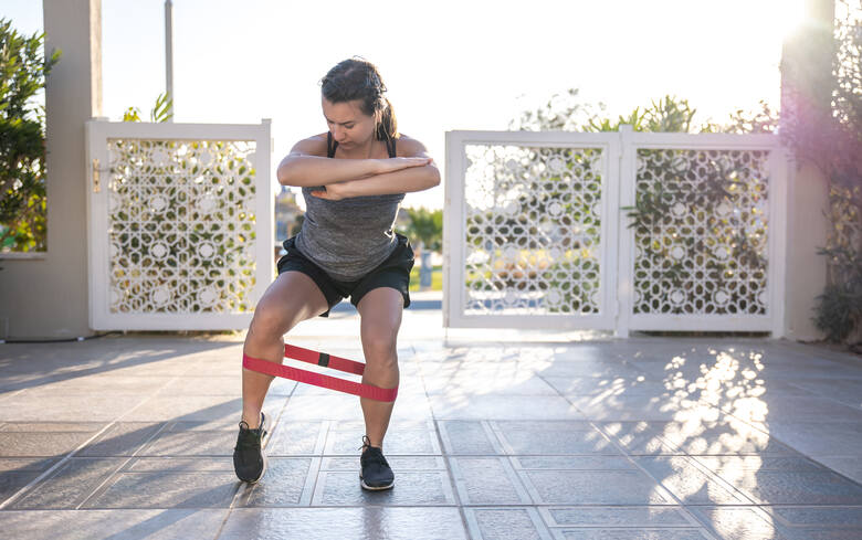Młoda kobieta ćwiczy nogi z gumą oporową w staniu