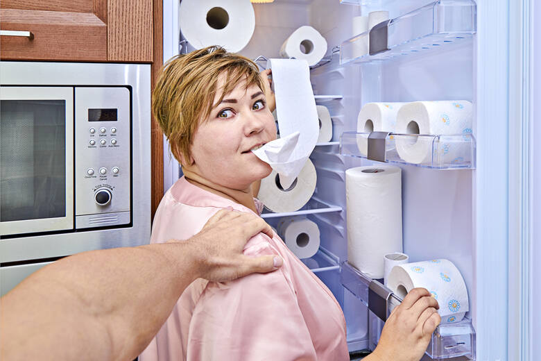 Kobieta wyjmuje papier toaletowy z lodówki i go zjada
