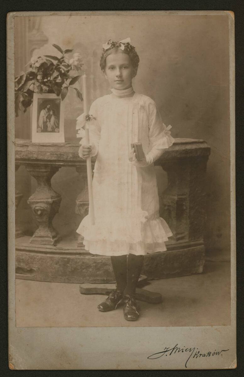 Dziewczynka w stroju komunijnym (widoczna podpórka podtrzymująca modelkę); atelier J. Mien przy ul. Kolejowej 11, ok. 1913. 