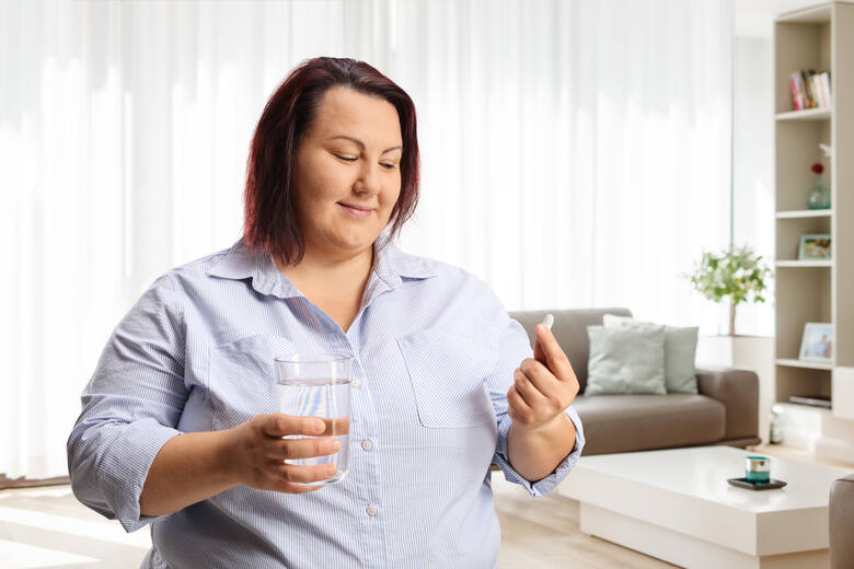 Otyła kobieta bierze tabletkę na otyłość