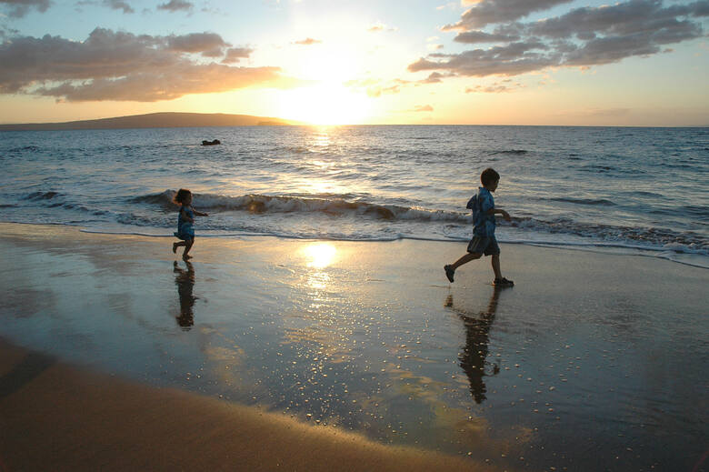 Dzieci biegnące po plaży o zachodzie słonca