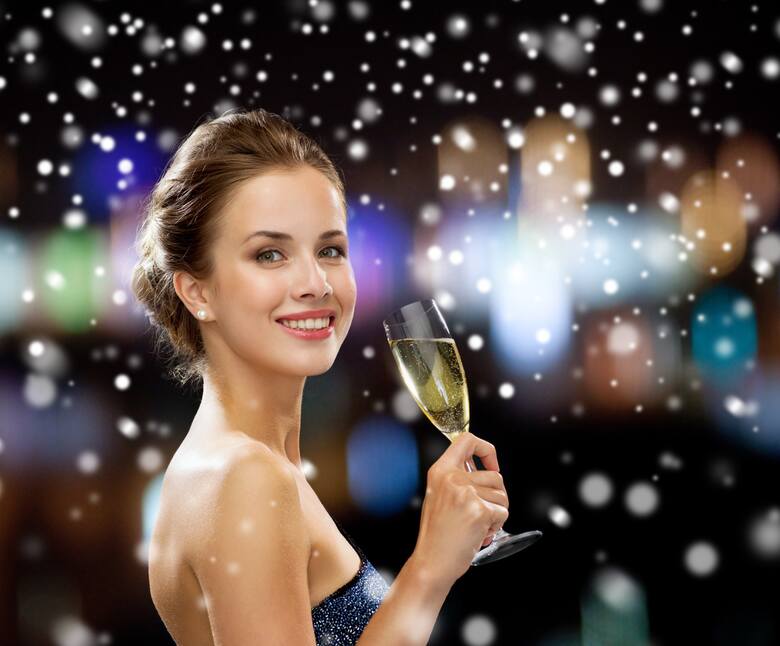 Młoda, ładna kobieta trzyma w ręku kieliszek z szampanem