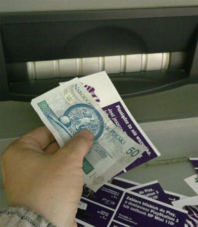 Bankomat Euronetu wydaje pieniądze i reklamowe ulotki.