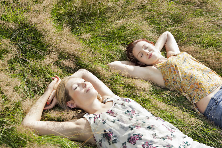 Dwie młode kobiety wygrzewają się w słońcu na łące