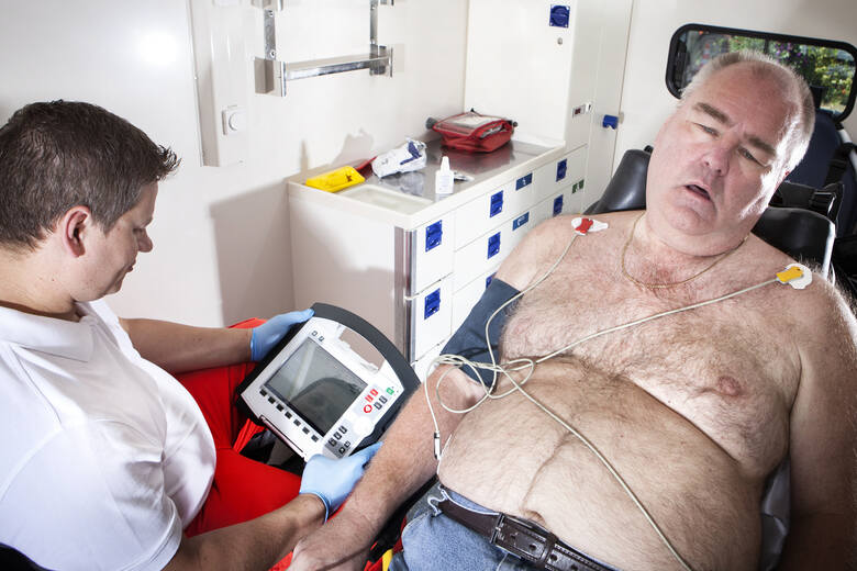 Starszy otyły mężczyzna źle się czuje podczas badania kardiologicznego