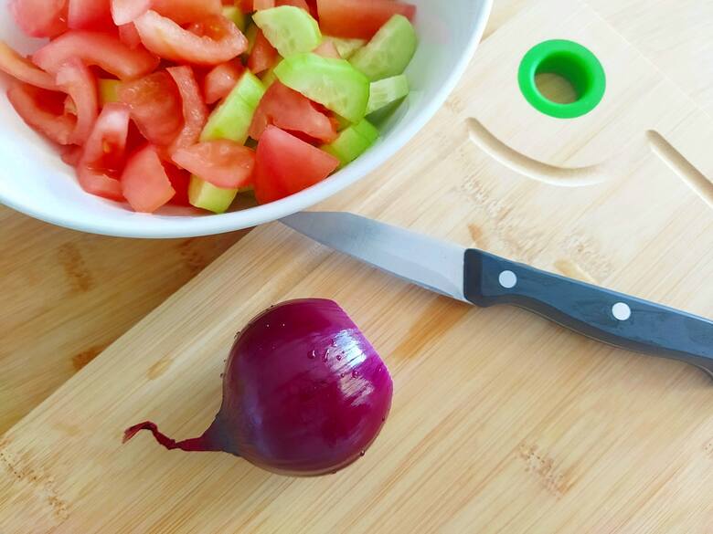 Cebulę posiekaj w piórka. Połącz wszystkie warzywa, dodaj oliwki i ser feta.