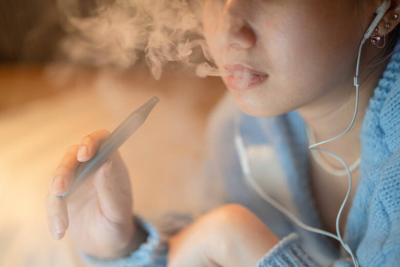 Młoda dziewczyna pali e-papierosa