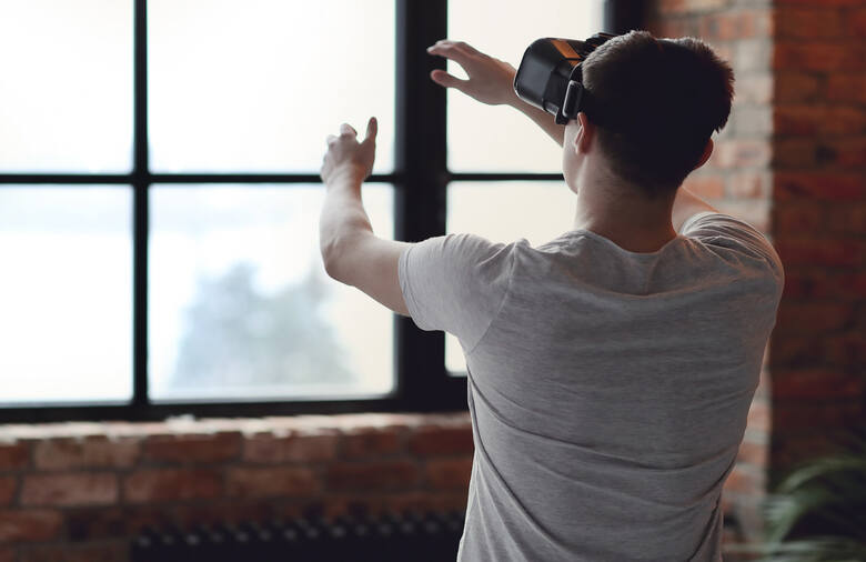 Młody mężczyzna stoi tyłem w okularach do wirtualnej rzeczywistości