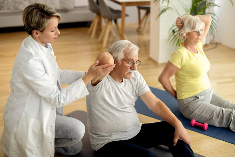 Fizjoterapeutka pomaga dojrzałej parze w ćwiczeniach fizycznych