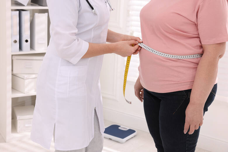 Dietetyczka mierząca talię kobiety z nadwagą za pomocą miarki