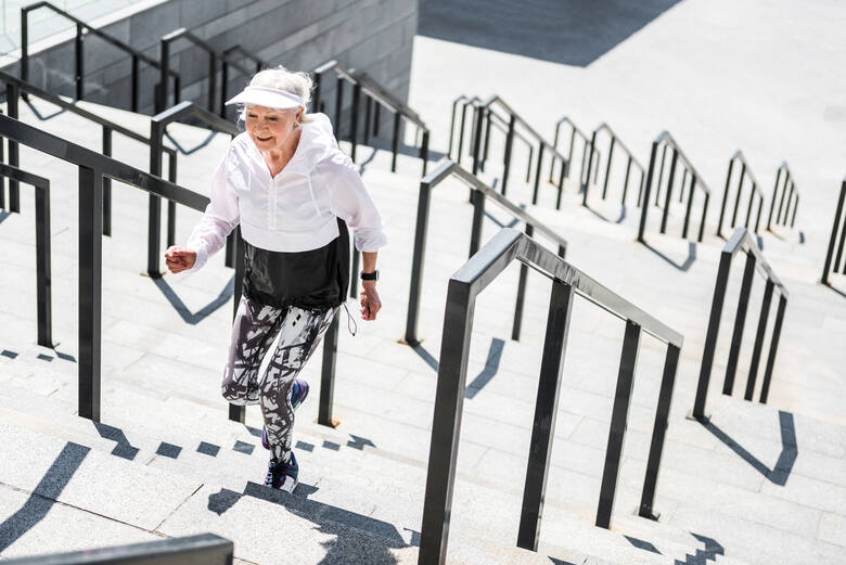 Starsza kobieta w sportowym stroju wchodzi po schodach