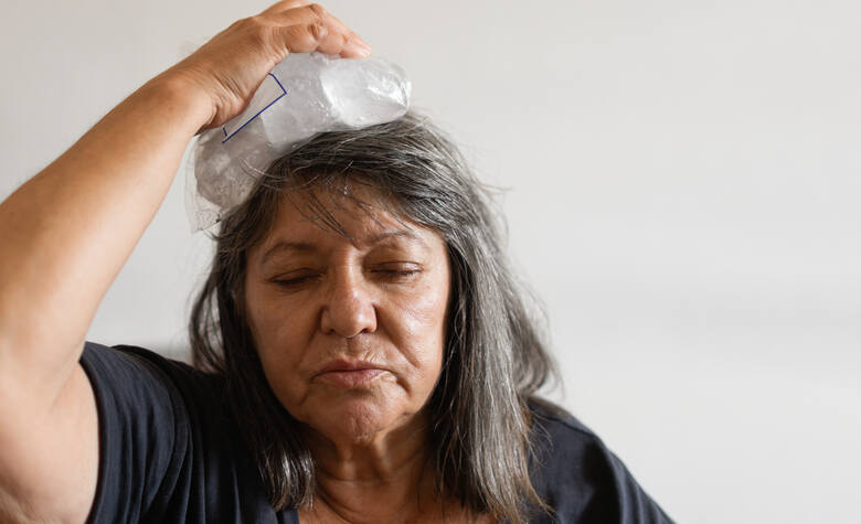Starsza kobieta ochładza się w upał kompresem na głowę