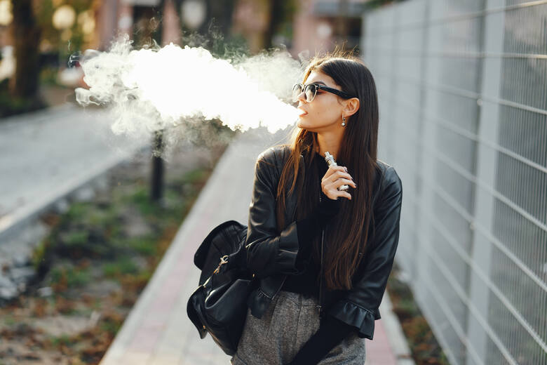 Kobieta paląca e-papierosa na ulicy