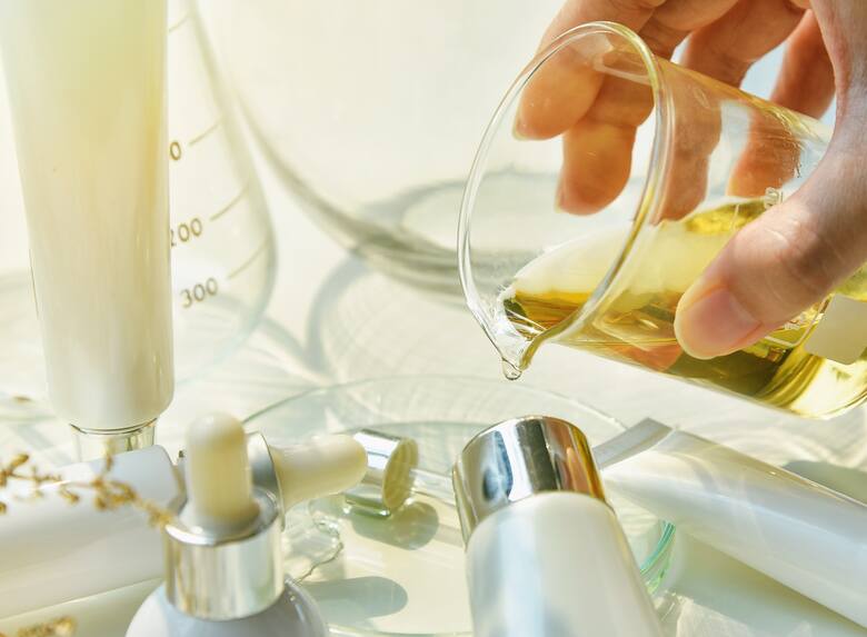 Szkło laboratoryjne i kosmetyki, ręka nalewa olej