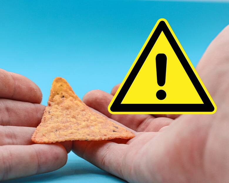 Pojedynczy chips Doritos w dłoniach i znak ostrzeżenia