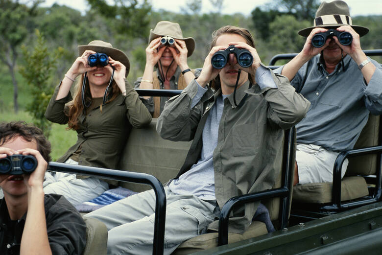 Grupa ludzi z lornetkami na safari