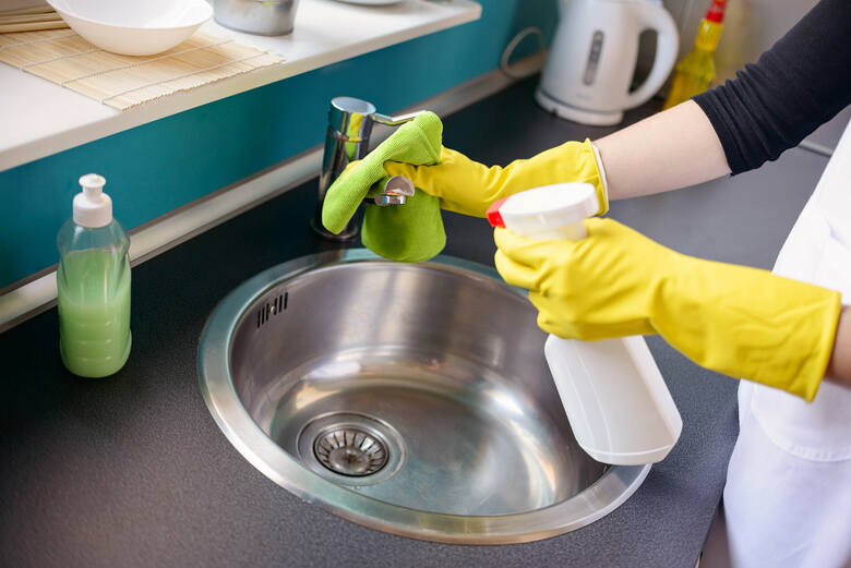 ręce kobiety w żółtych rękawiczkach mycie zlewu w kuchni