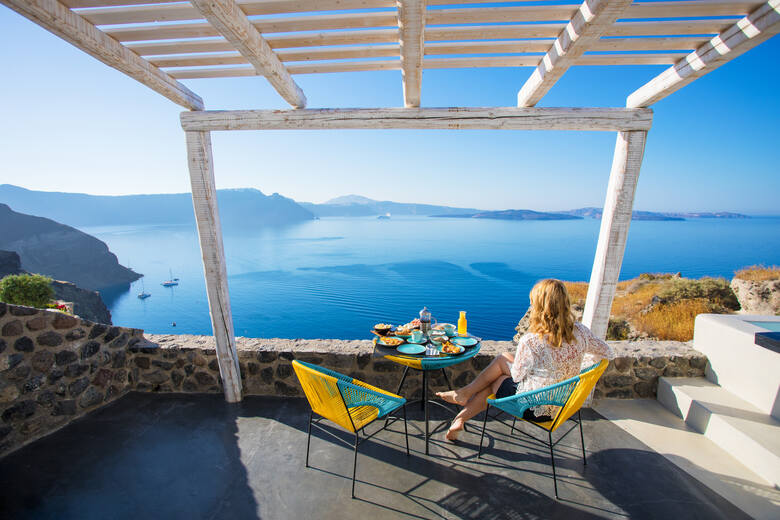 Turystka przy stoliku z jedzeniem i napojami na Santorini 