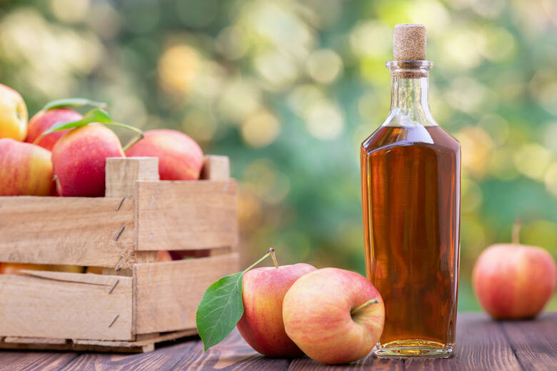 Jabłka w skrzynce i alkohol w butelce na stole