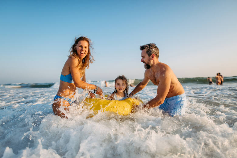 Szczęśliwi rodzice z córką dbają o jej bezpieczeństwo podczas kąpieli w morzu