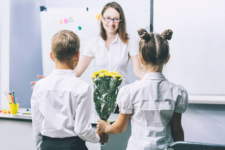 uczniowie dają nauczycielce kwiaty 