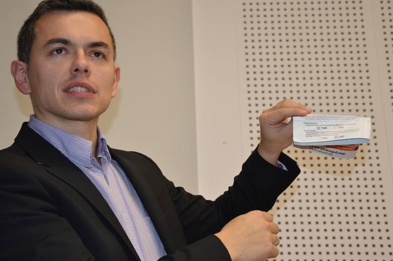 Kamil Kaczmarek z ulotką zachęcającą do głosowania i pokazującą, na jakie pytania trzeba odpowiedzieć