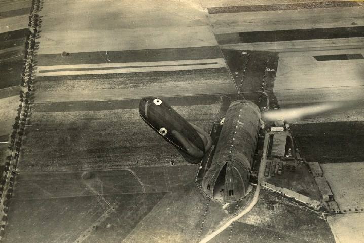 Zdjęcie hali Zeppelina z takiej perspektywy i do tego z balonem zaporowym.<br /> Dla niewtajemniczonych, na fotografii panorama obecnej ulicy Serbskiej, ale bez wszechobecnych osiedli. Obrazek pochodzi zapewne z 1919 roku i został zrobiony chwilę po przejęciu hali wraz z samolotami, które...