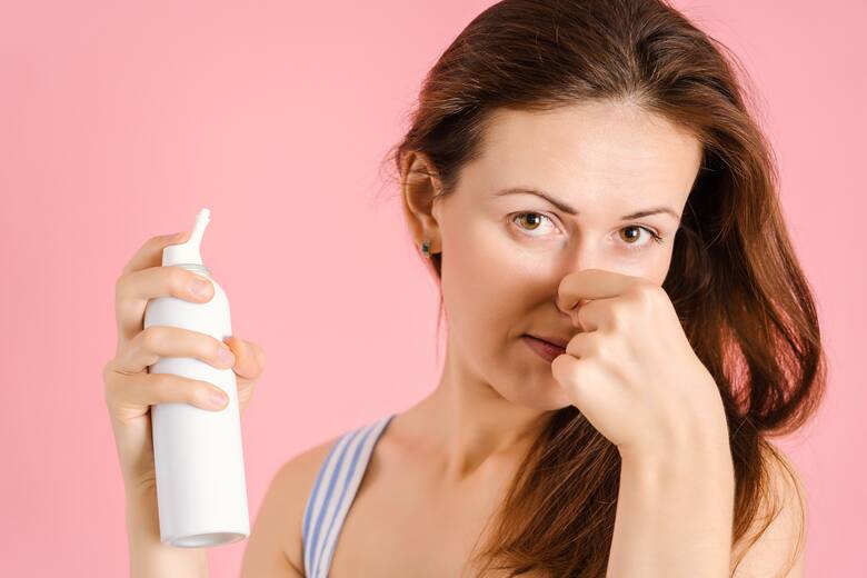Młoda kobieta trzyma w ręku spray do płukania nosa