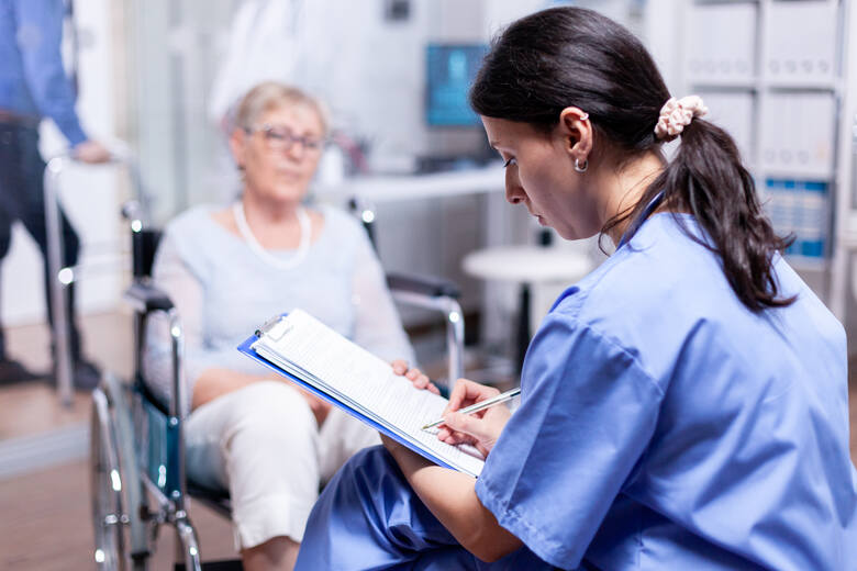 Starsza kobieta na wózku rozmawia z pracowniczką szpitala