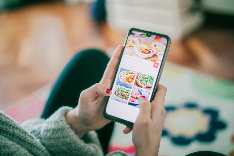Kobieta ogląda zdjęcia potraw na smartfonie