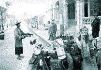 Fot. archiwum rodzinne pp. Twardowskich: Na mecie w Chinach. Halina Bujakowska pozuje przy motocyklu z biało-czerwonym proporczykiem na kierownicy.
