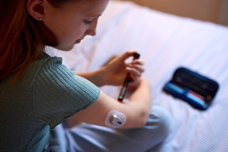 Młoda kobieta z systemem monitorowania cukrzycy CGM przyjmuje lek w zastrzyku